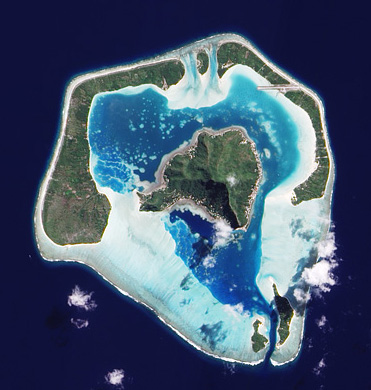 A satellite image of Maupiti, an almost atoll in the Society Islands Chain. Fringing reef appears pale blue. Credit: NASA Earth Observatory