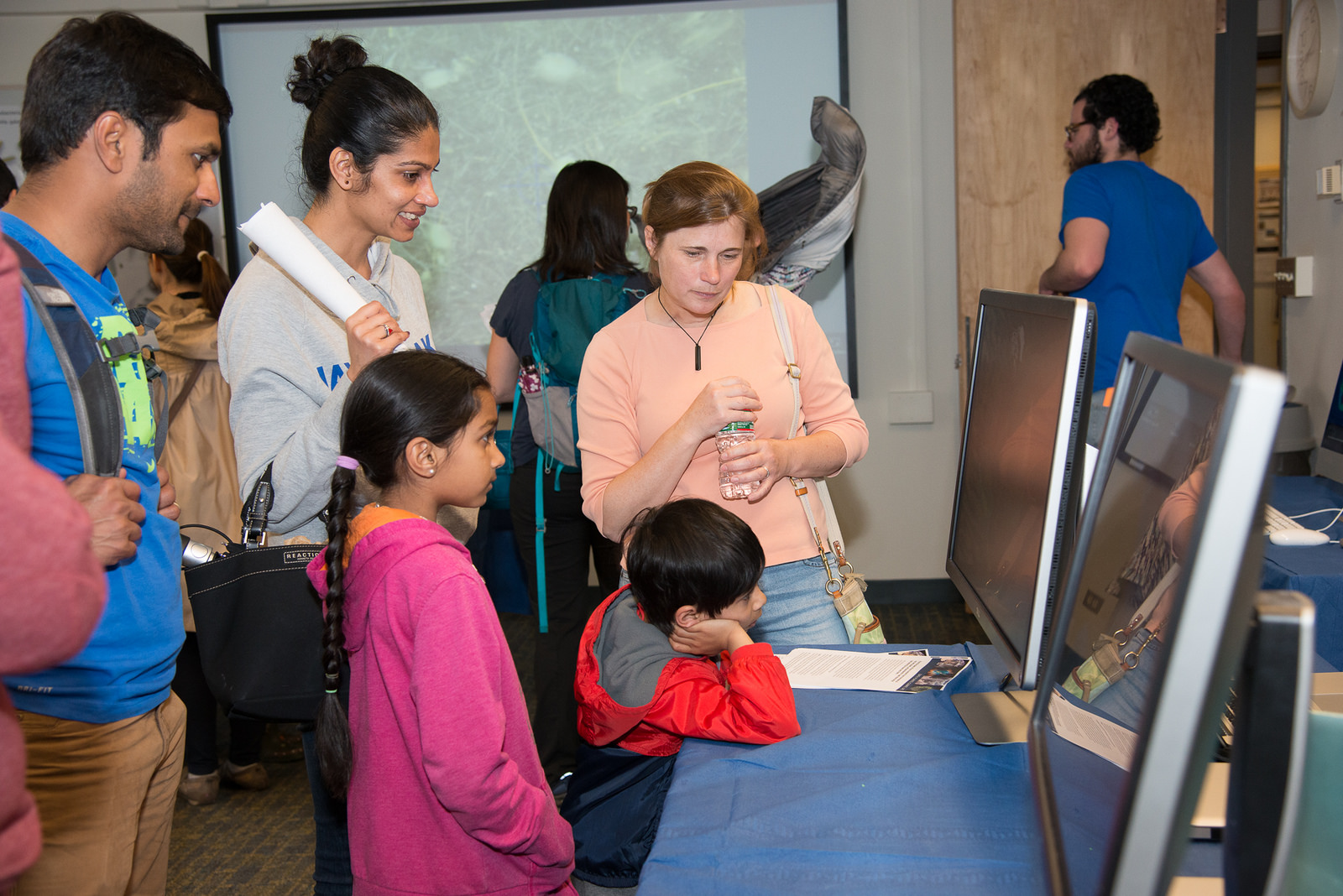A family watches videos of global ocean currents and chlorophyll from phytoplankton as EAPS Research Scientist Stephanie Dutkiewicz explains (Image: Vicki S McKenna)